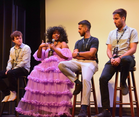 A group of people sitting in a row on stools and holding microphones